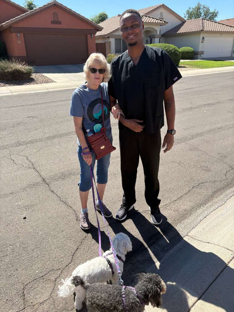 Caregiver walking with senior client and her dogs